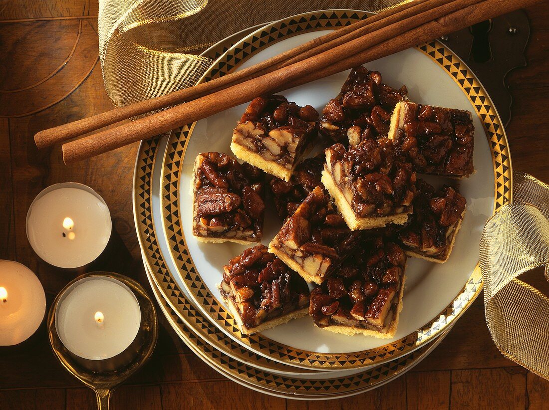 Pecan squares with cinnamon sticks on plate; candles