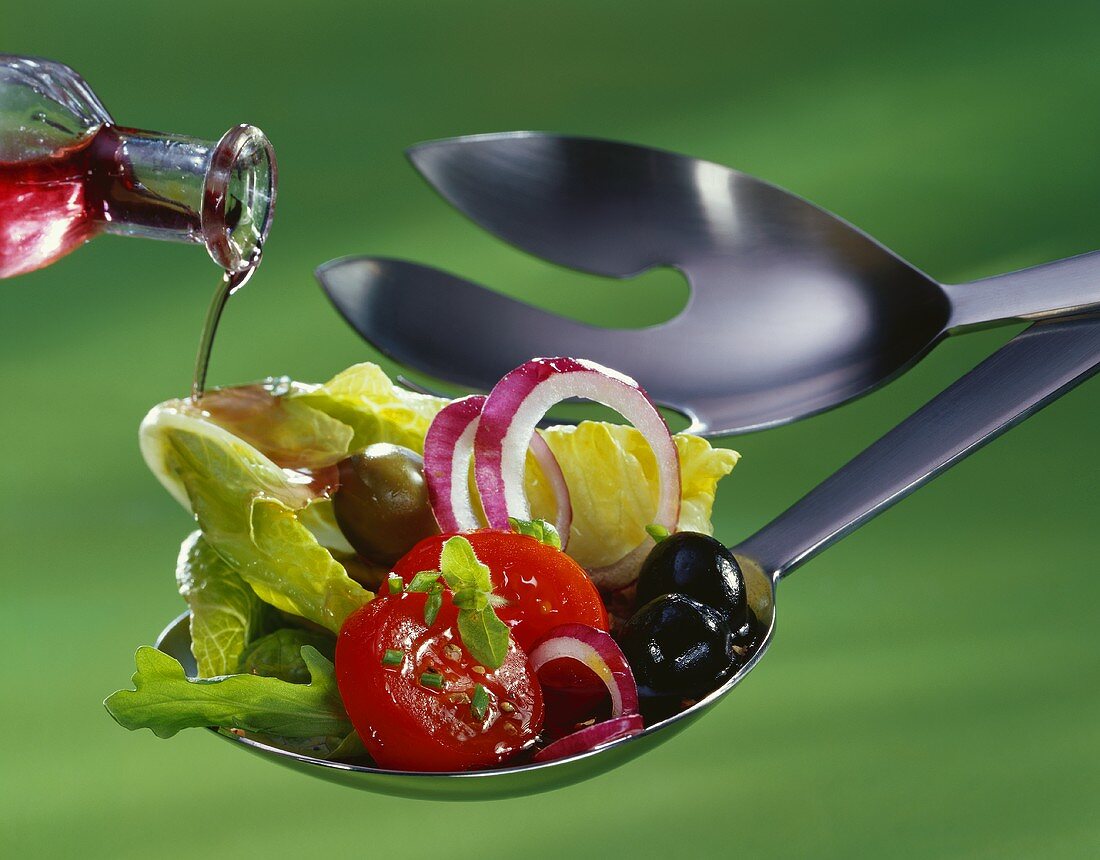 Pouring vinegar on to spoon over salad