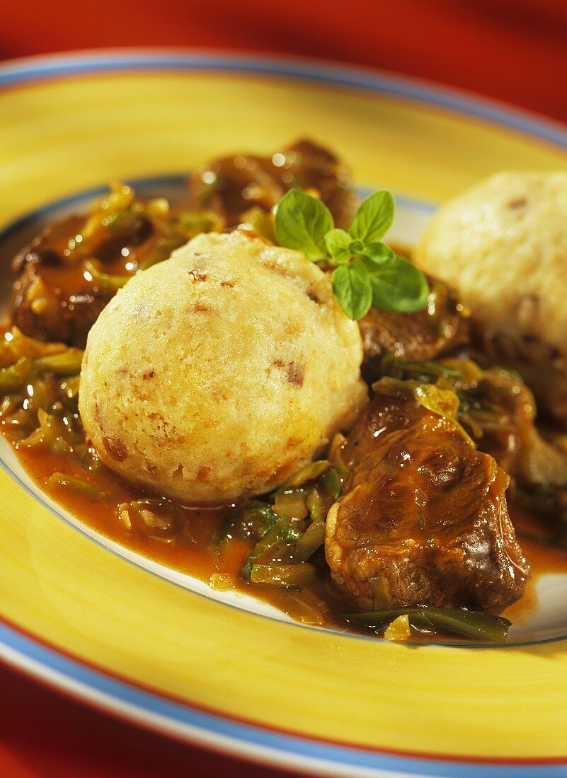 Cabbage goulash with bacon dumplings on yellow plate