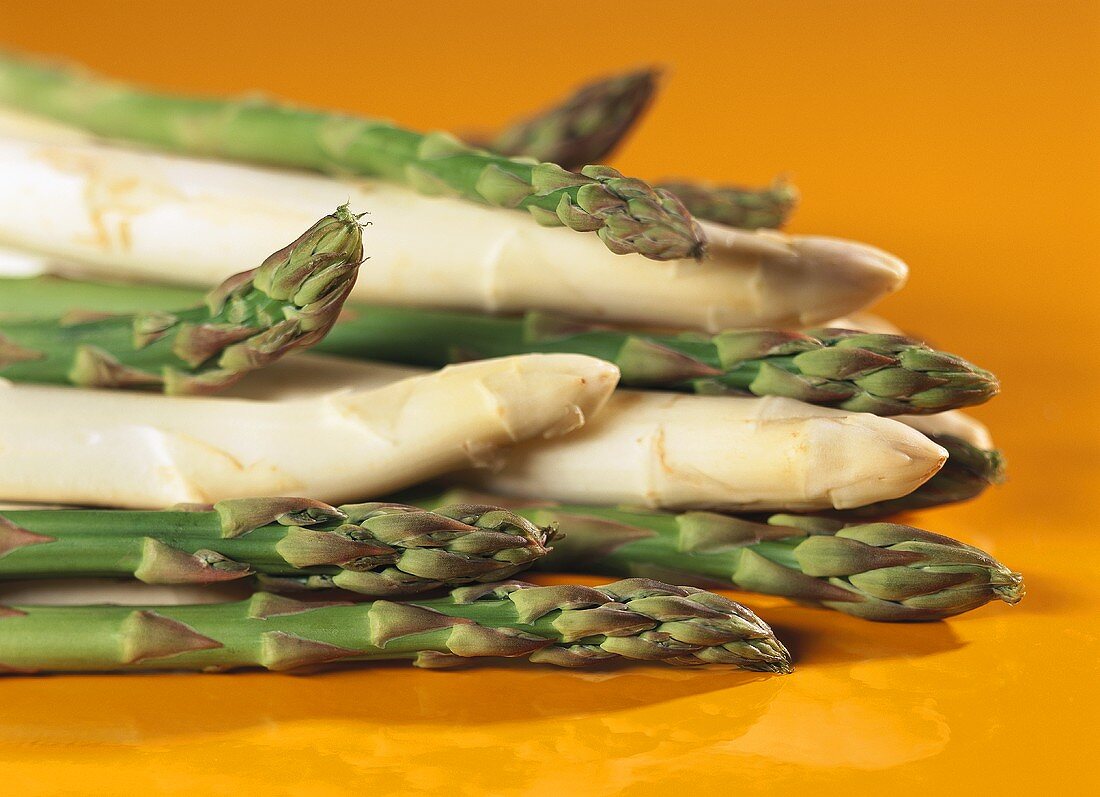 White and green asparagus on orange background
