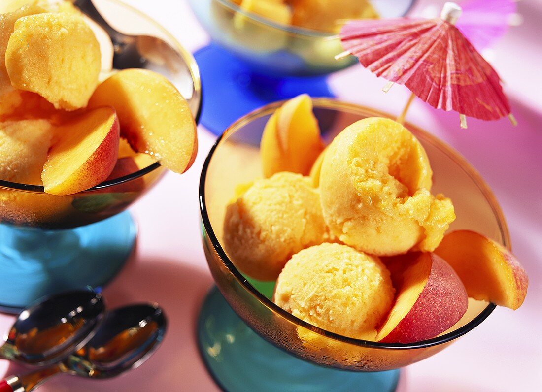 Mango and peach ice cream with peach slices and parasol
