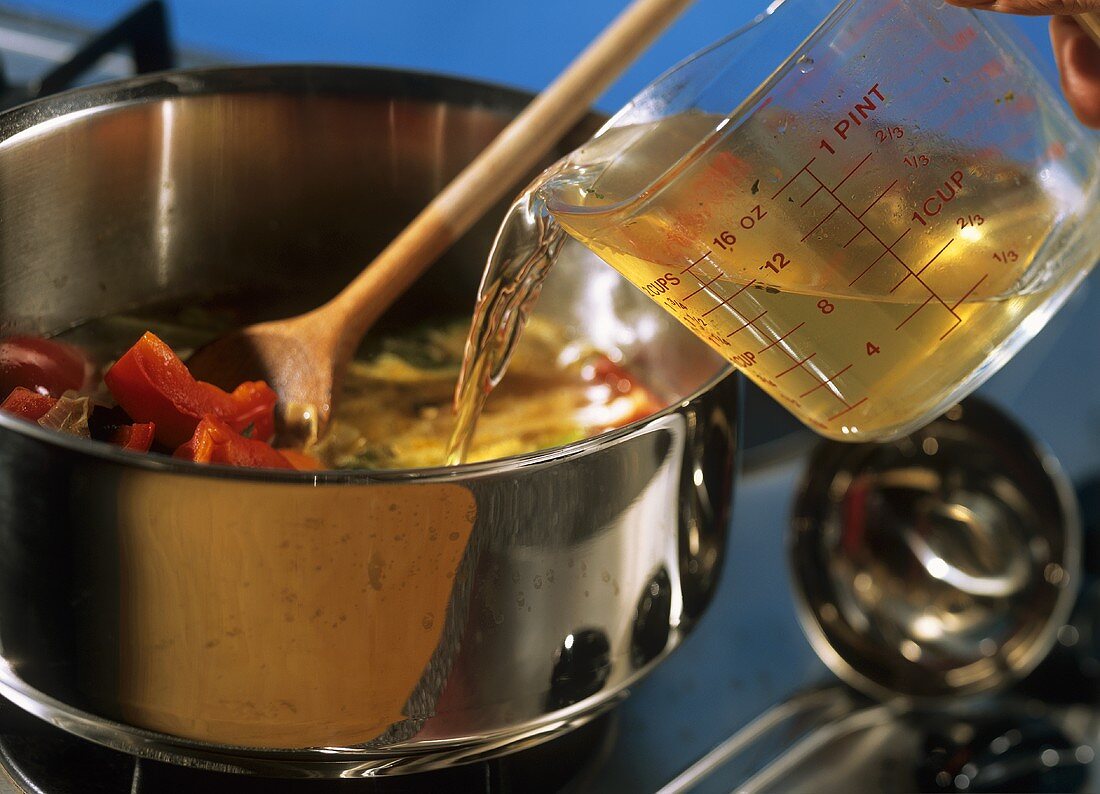 Pouring stock into pan of vegetables