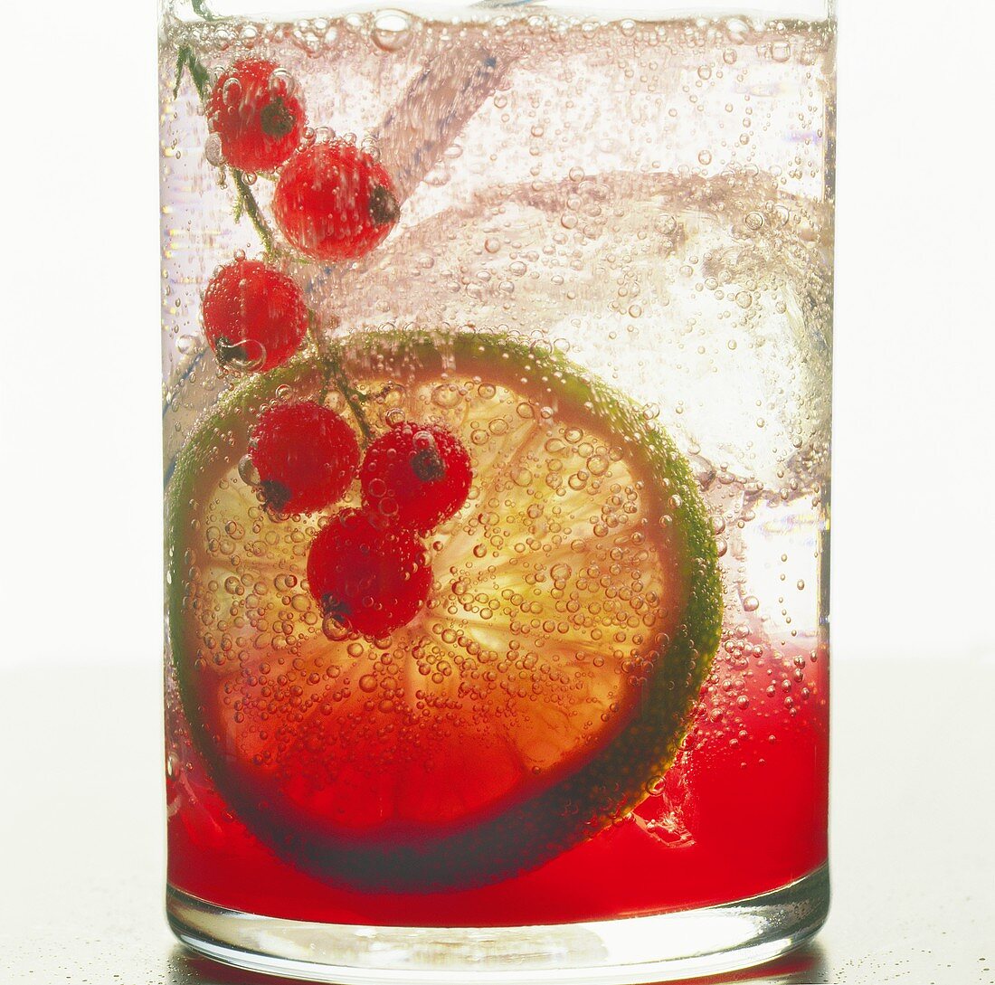Fruit drink with redcurrants, lime and ice cubes