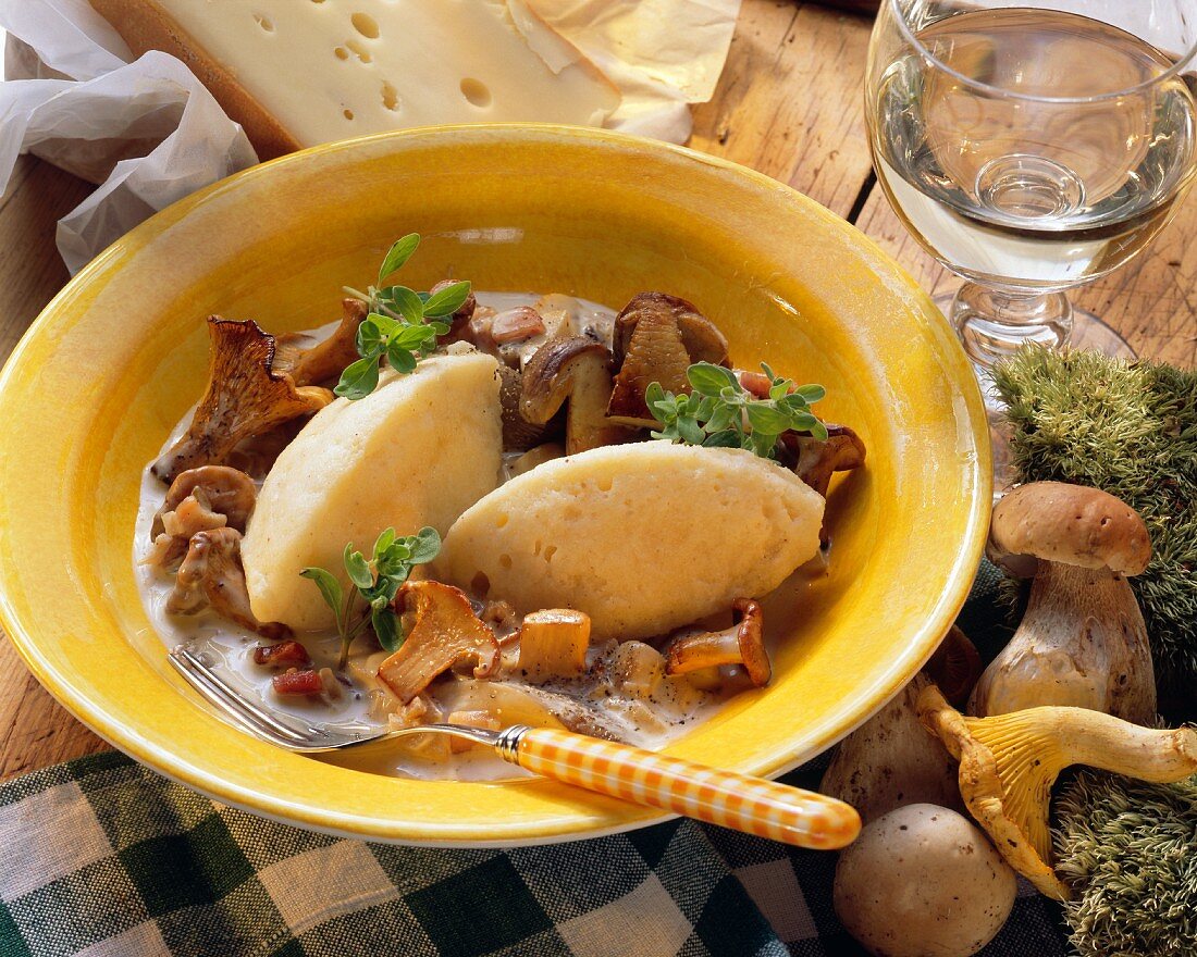 Pilzragout mit Käseklössen auf gelbem Teller