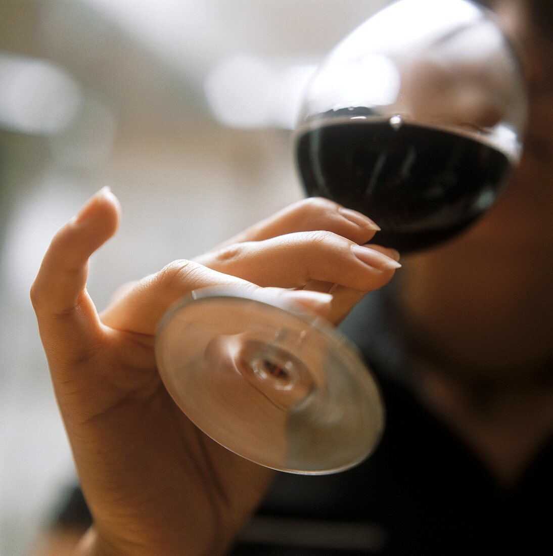 Hand holding red wine glass in an affected way