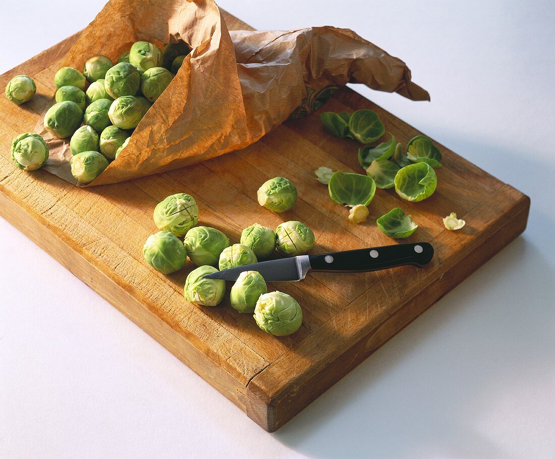 Brussels sprouts, some in paper bag, on chopping board