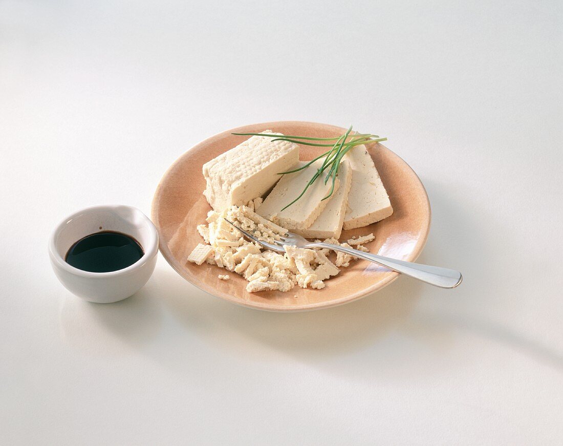 Tofu auf Teller und ein Schälchen Sojasauce
