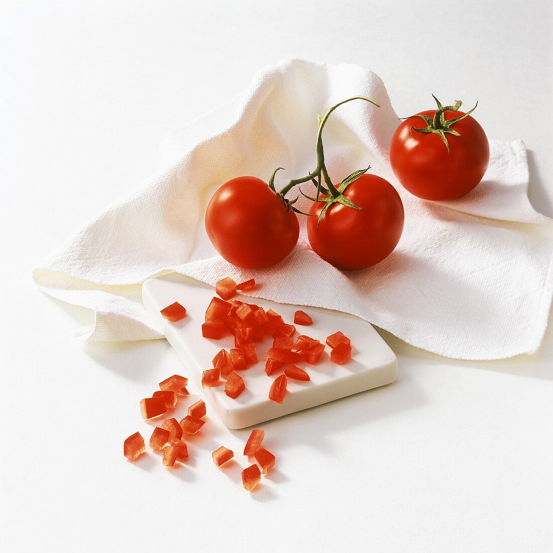 Strauchtomaten und Tomatenwürfel auf Tuch und Schneidebrett