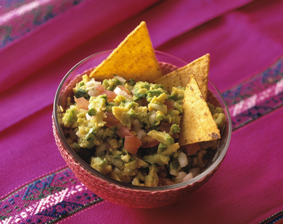 Guacamole with tortilla chips in a glass bowl