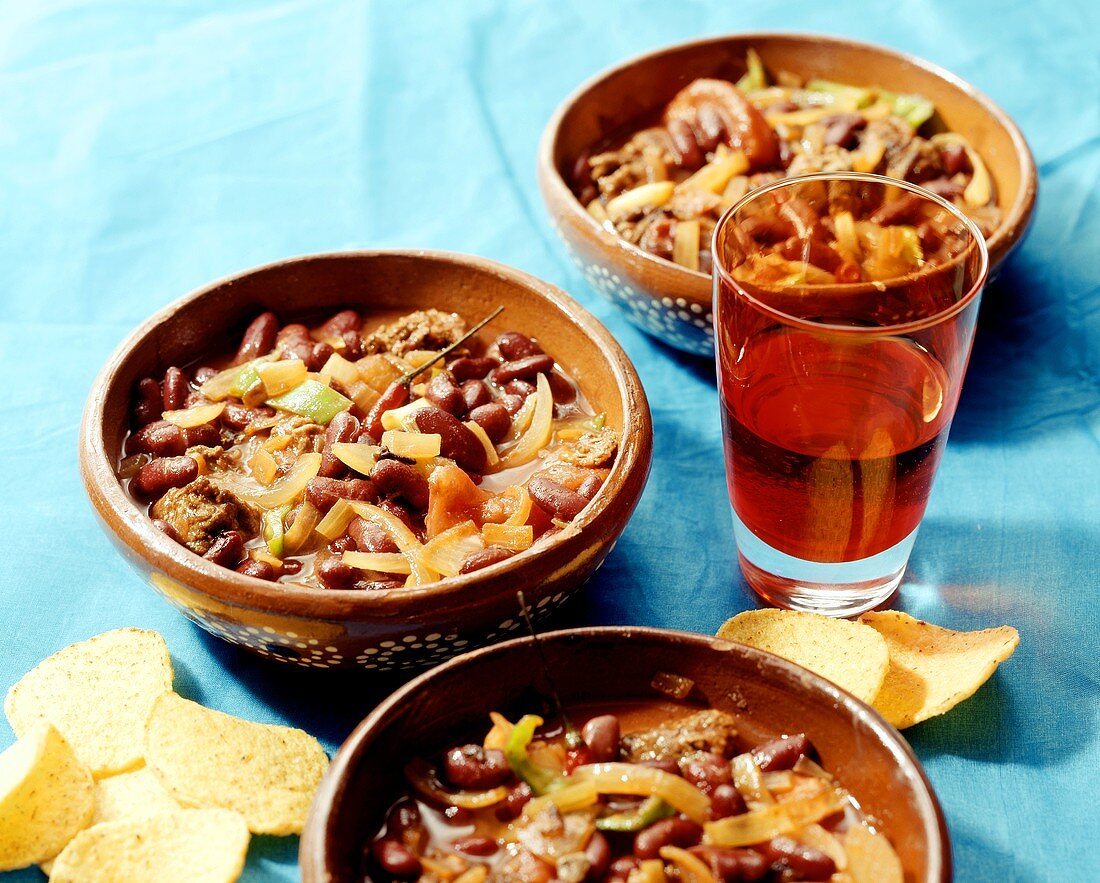Chili con carne in earthenware dishes; red wine; tortilla chips