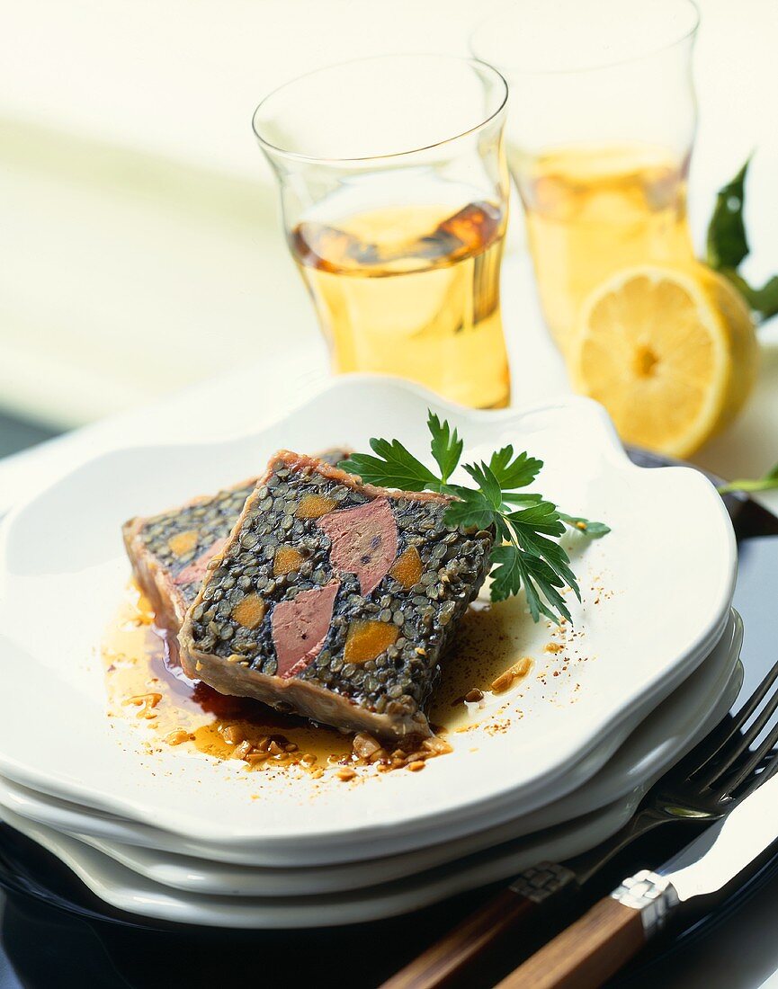 Linsenterrine mit Gänseleber auf einem Tellerstapel