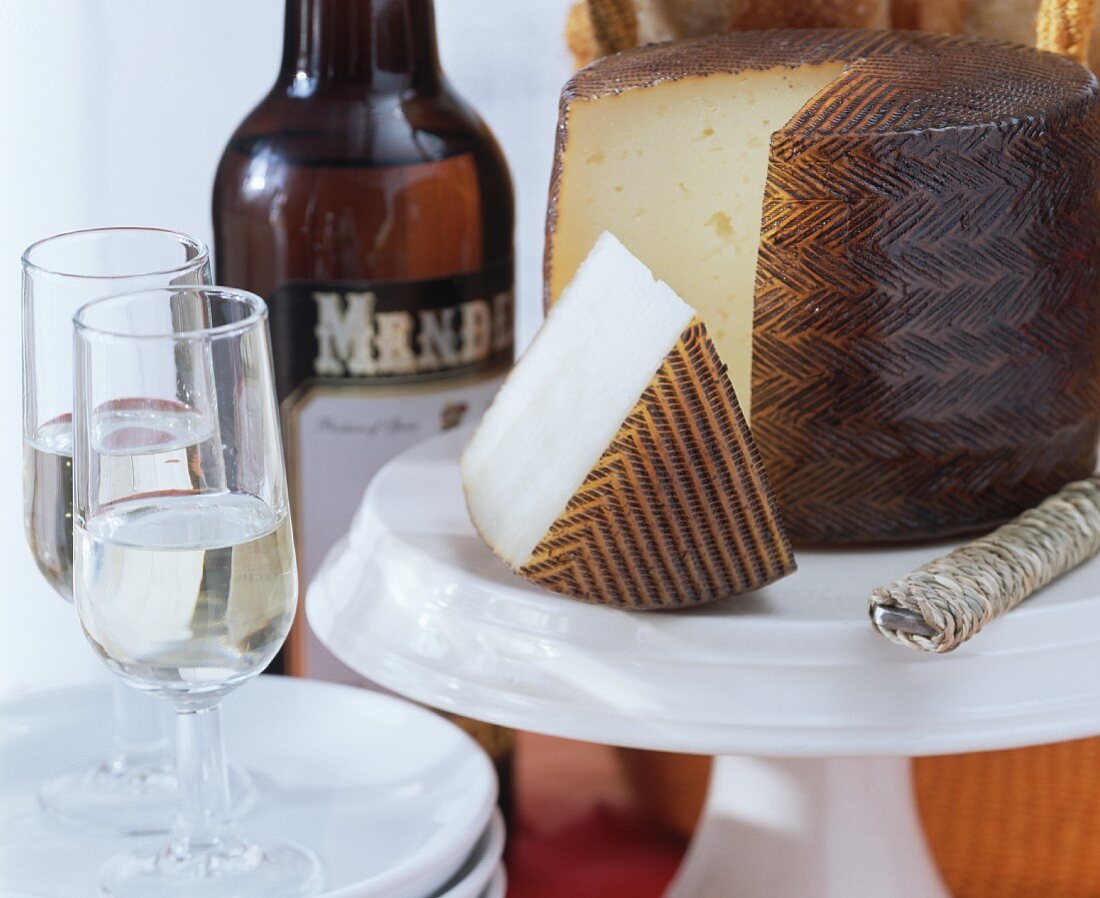 Angeschnittener Manchego mit Sherrygläsern und Sherryflasche