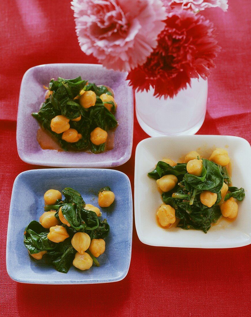 Kichererbsen-Spinat-Salat auf kleinen Tellern; rote Nelken
