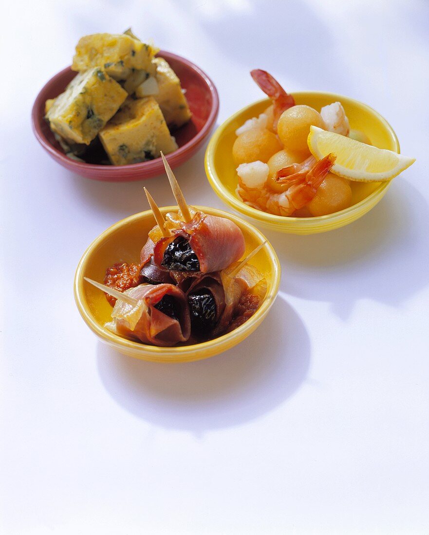 Three different tapas in colourful bowls