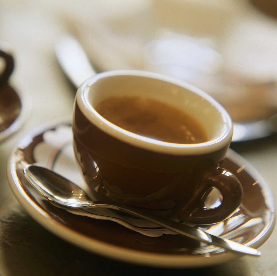 Espresso in brauner Espressotasse mit Löffel auf Untertasse
