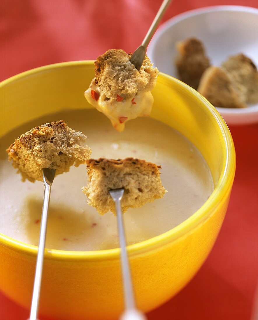 Cheese and chili fondue with bread cubes on fondue forks