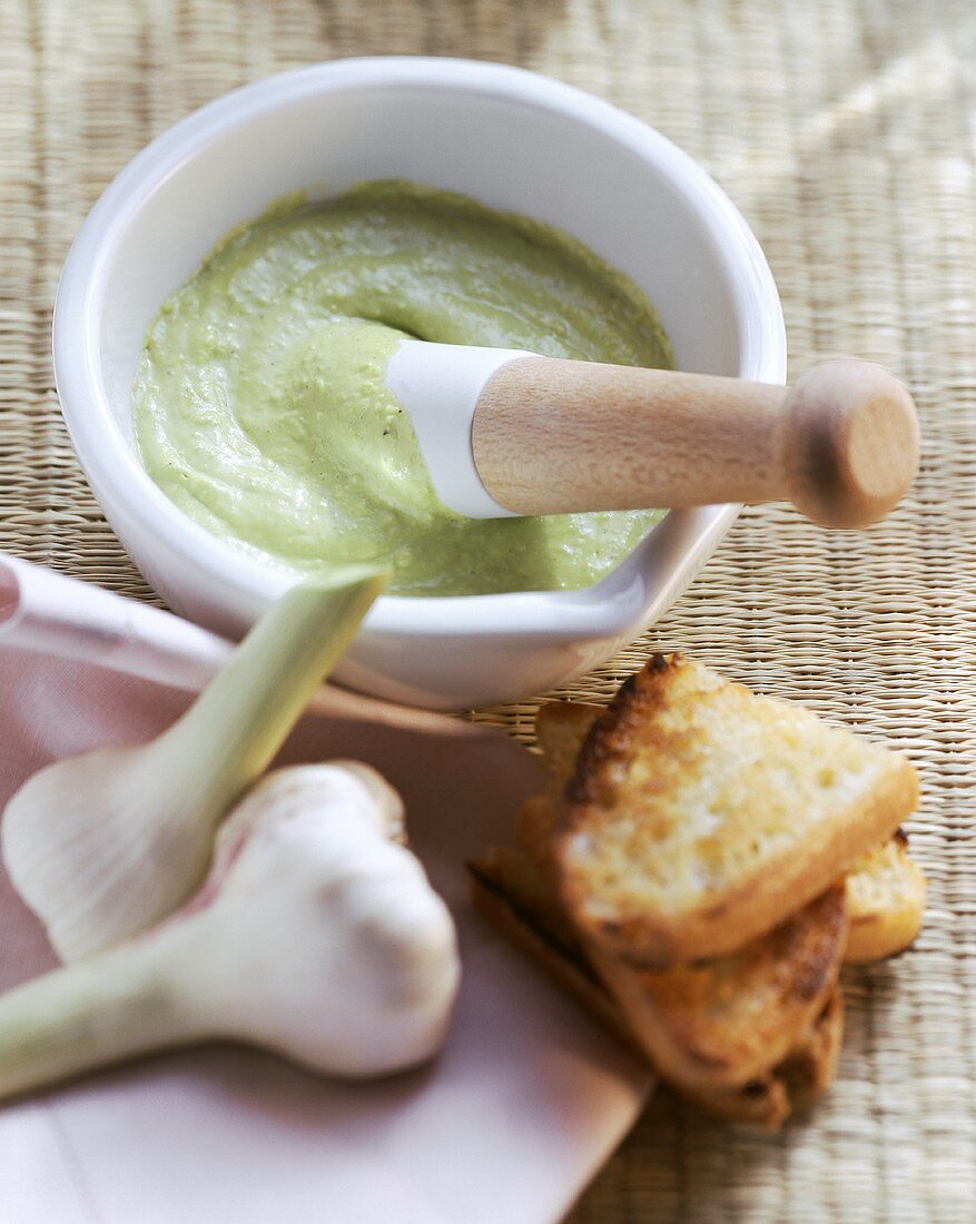 Garlic mayonnaise with avocado in mortar; toasting bread