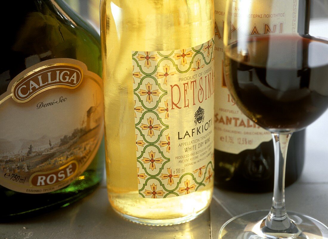 Verschiedene griechische Weinflaschen und ein Rotweinglas