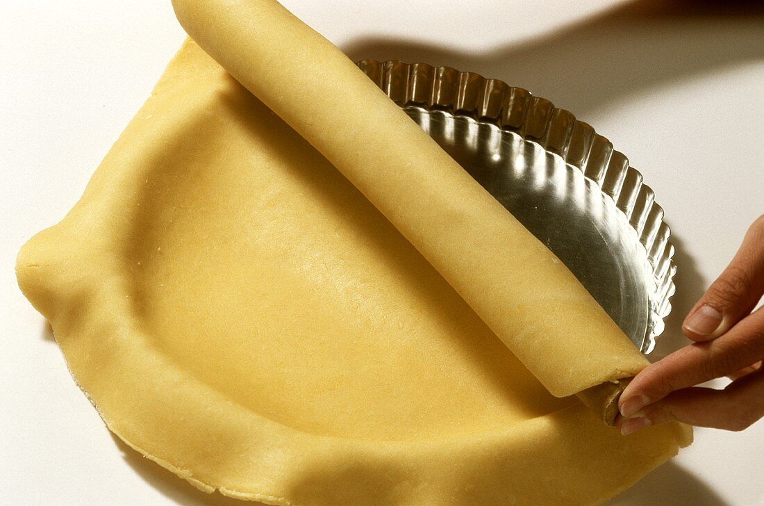 Placing pastry in tart tin using rolling pin