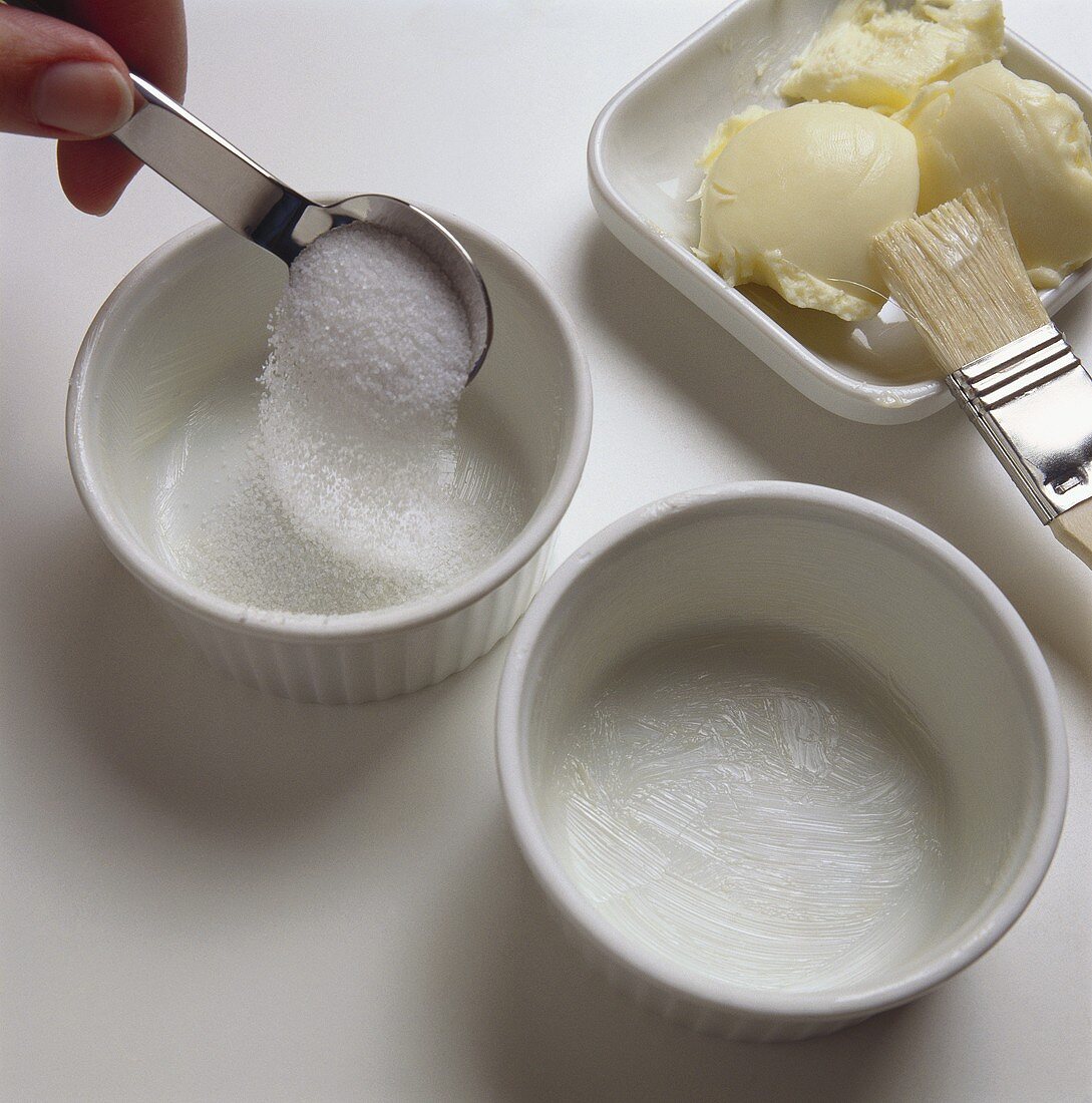 Sprinkling sugar in buttered dessert moulds