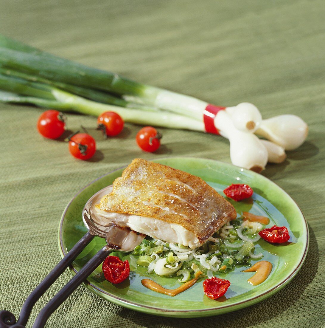 Cod on spring onions with cherry tomatoes