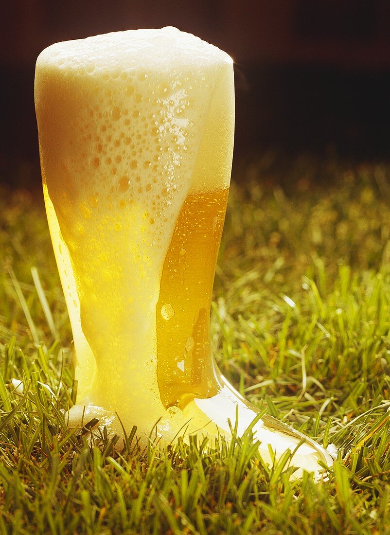 Überschäumendes helles Bier in einem stiefelförmigen Glas