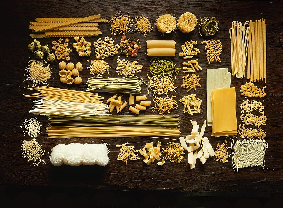 Many different types of pasta on dark wooden background