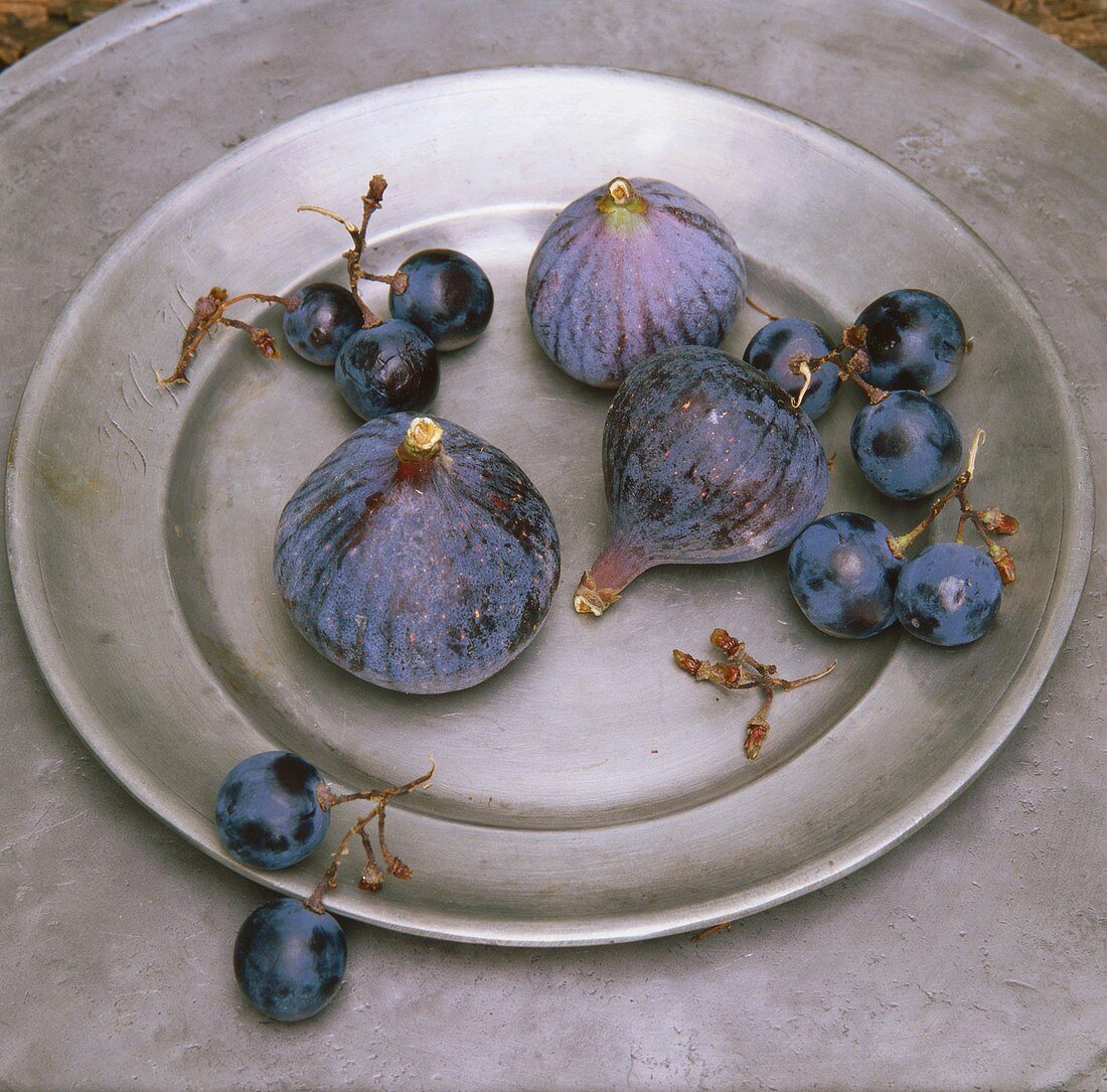 Figs and blue grapes on pewter plate