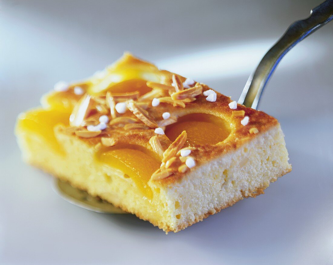 A piece of apricot cake with flaked almonds and sugar