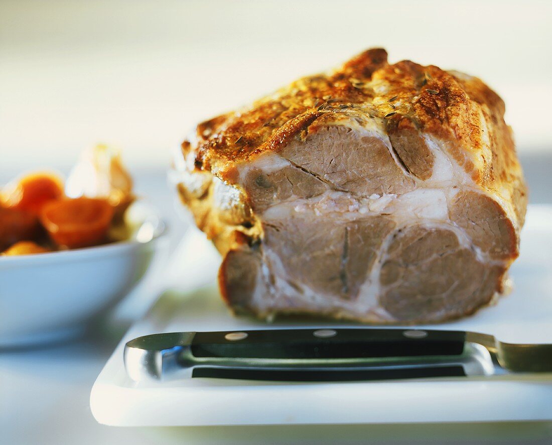 Roast pork on chopping board with knife