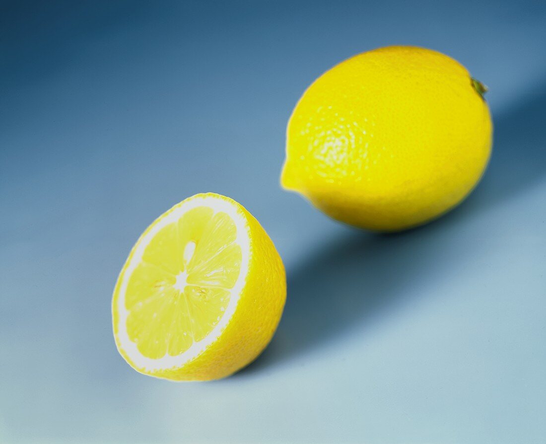 Ganze und halbe Zitrone auf blauem Untergrund