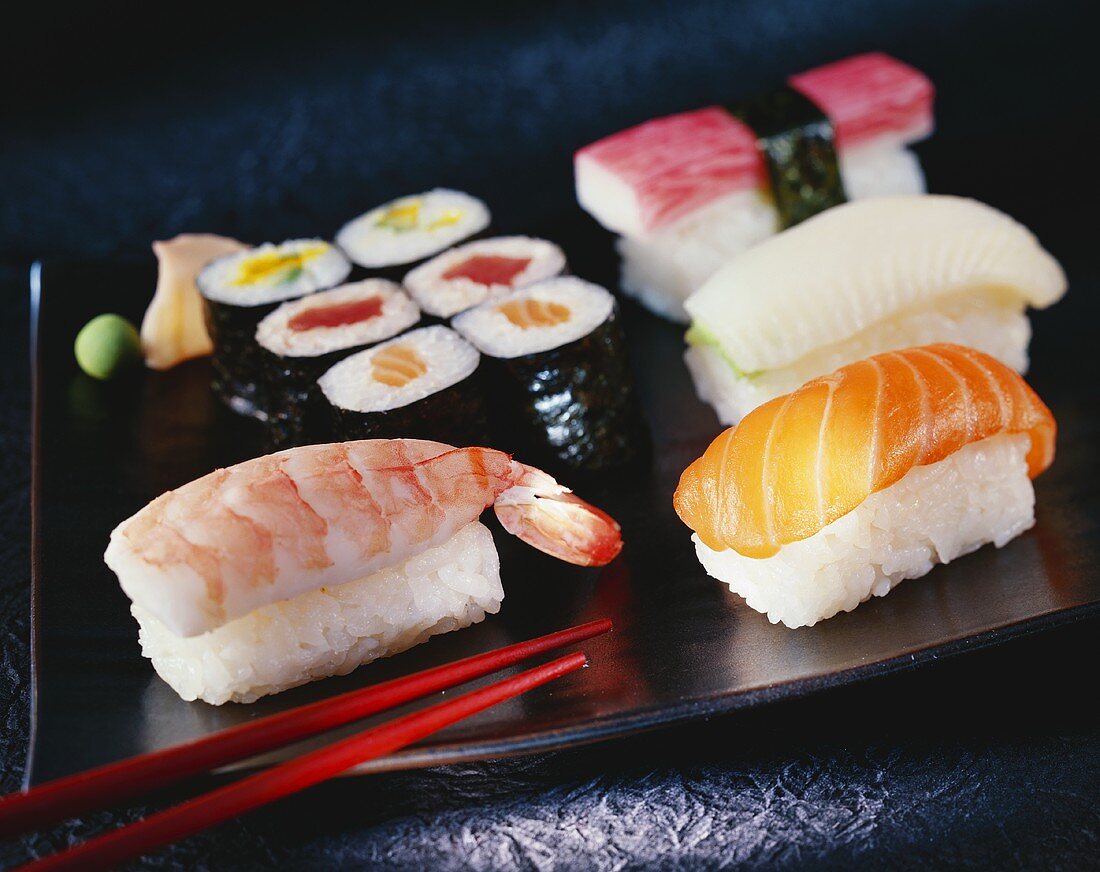 Sushi auf brauner Platte mit Stäbchen
