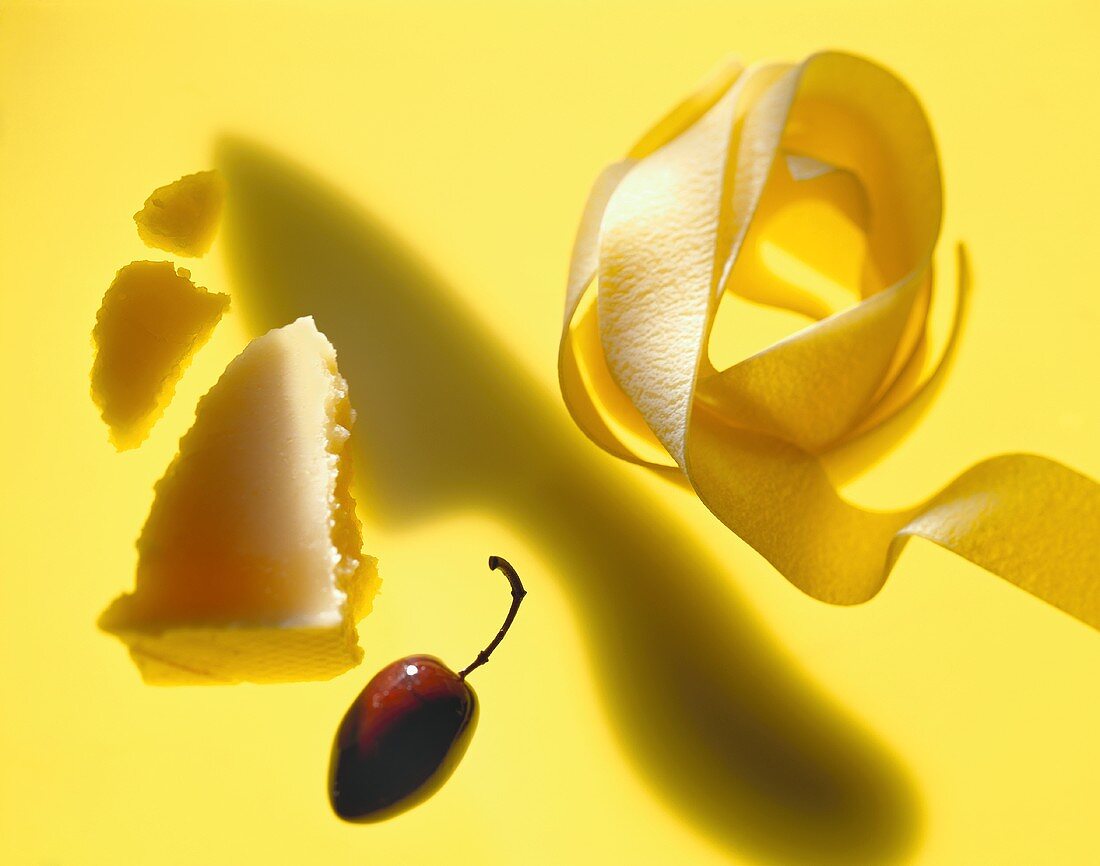 Bandnudeln, Parmesan und Olive vor gelbem Hintergrund