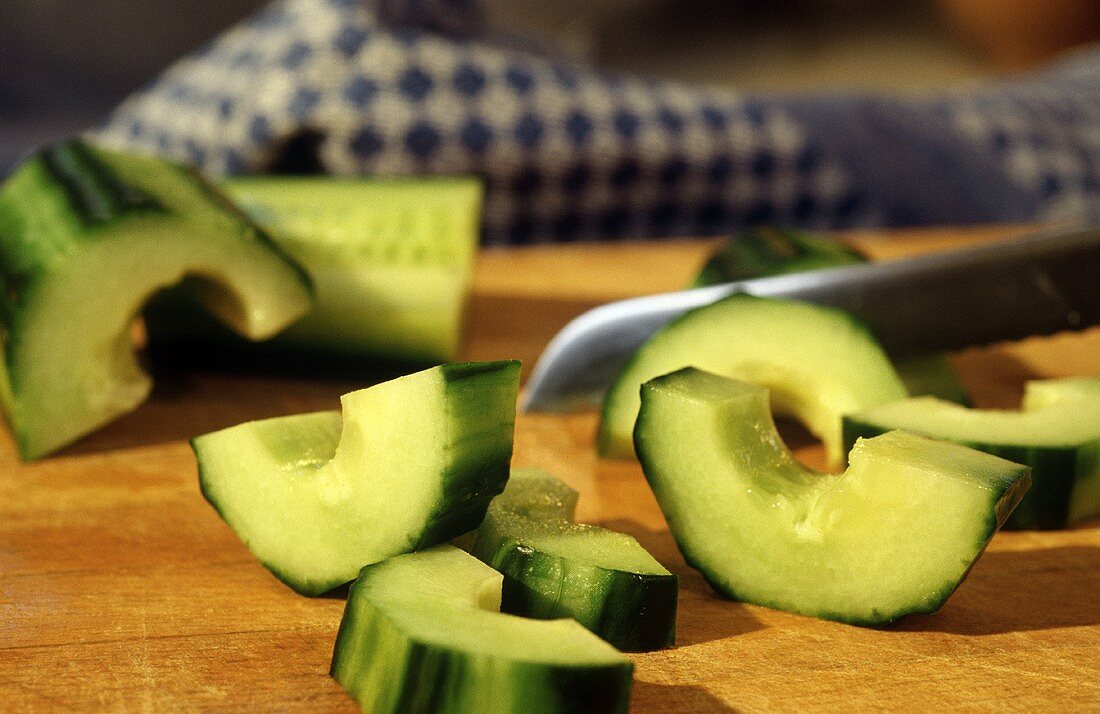 Thick cucumber slices on a wooden platter with a knife
