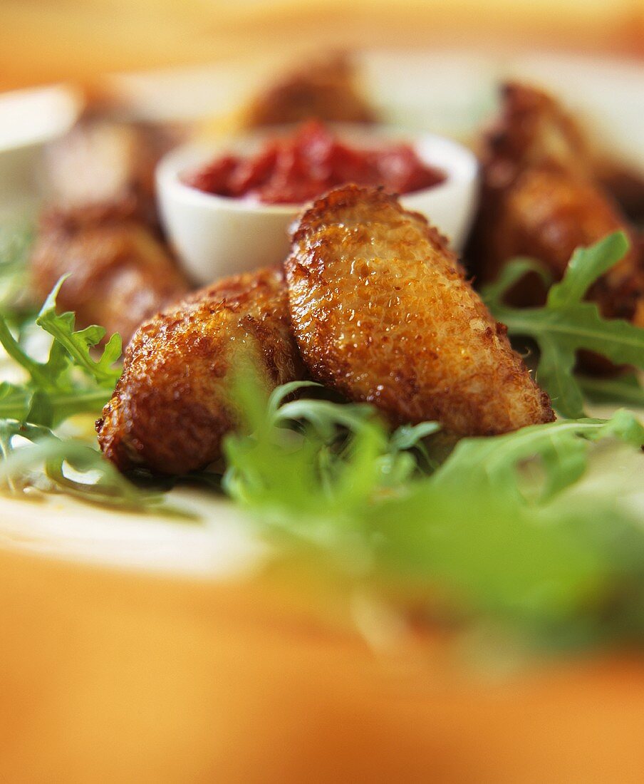 Chicken wings with salsa dip, garnished with rocket, on plate