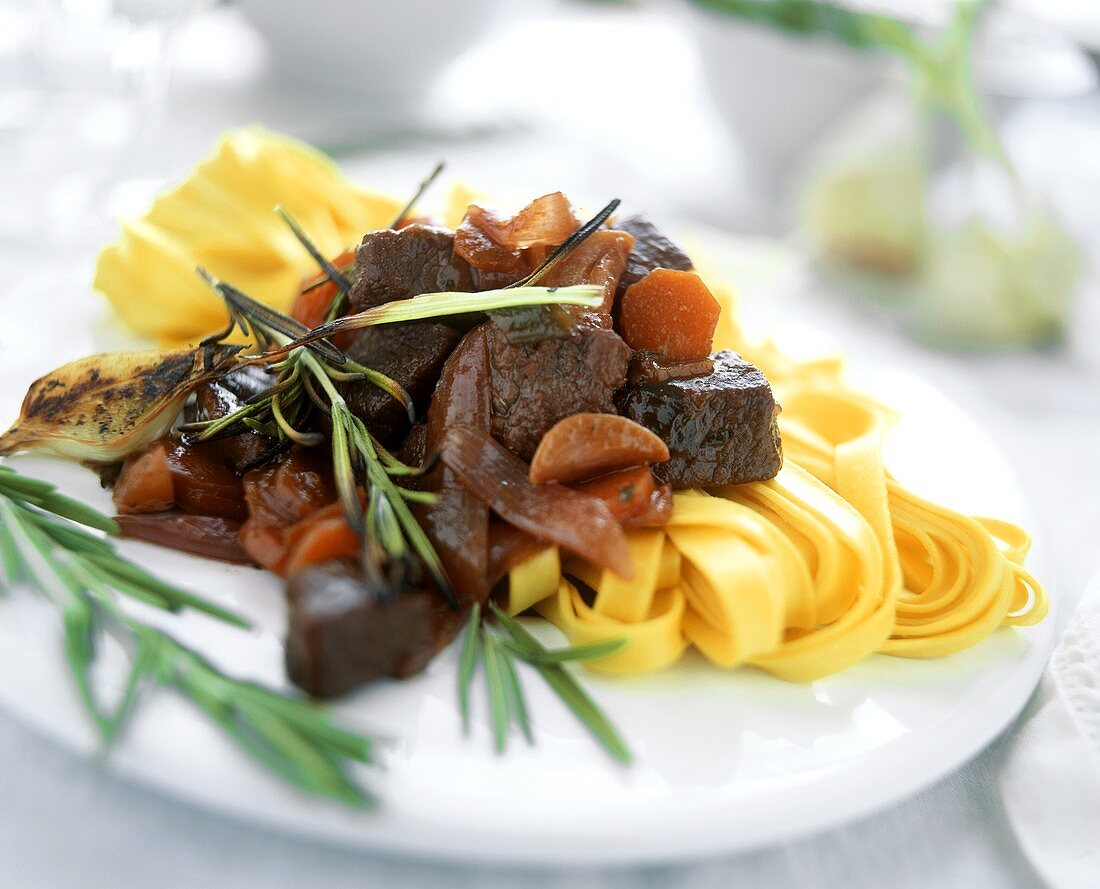Lamb goulash with rosemary and ribbon noodles on plate