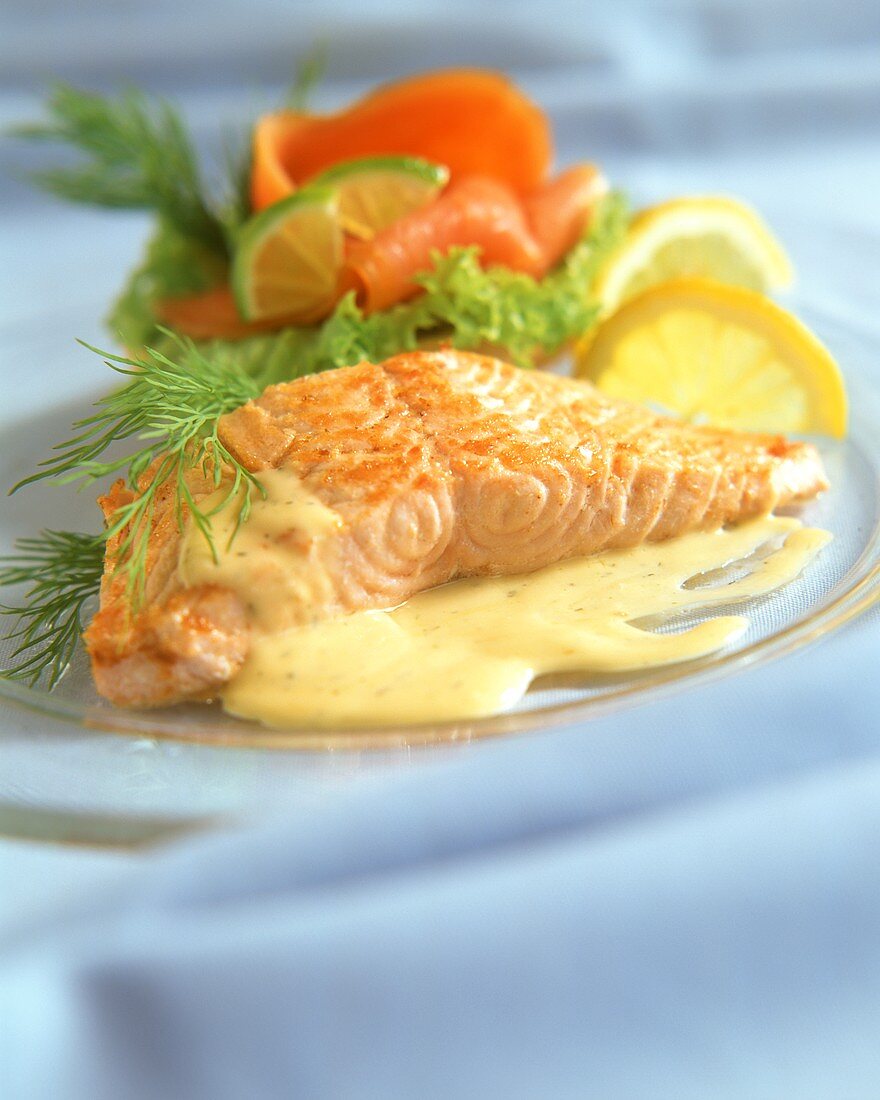 Fried salmon fillet with sauce and salmon roll on plate