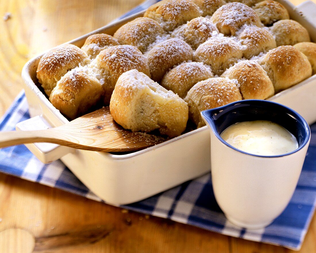 Frisch gebackene Buchteln in der Backform; Vanillesauce