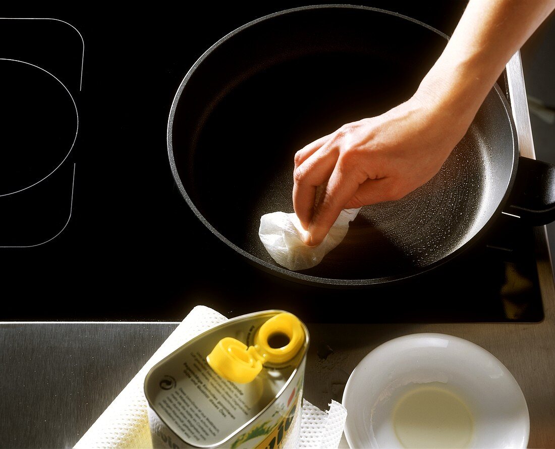 Rubbing a coated pan with oil-soaked cloth