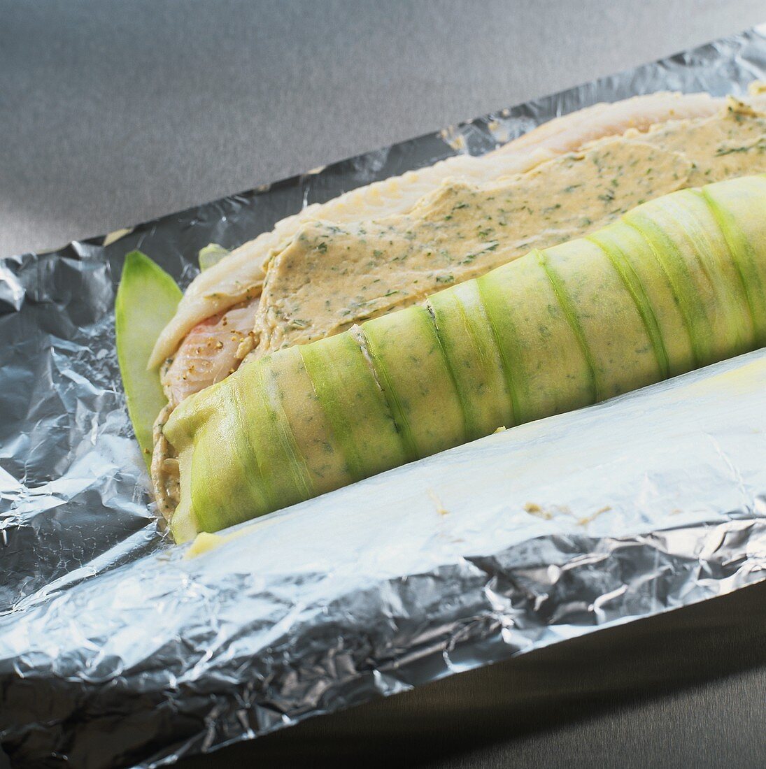 Rolling up salmon and plaice roulade in aluminium foil