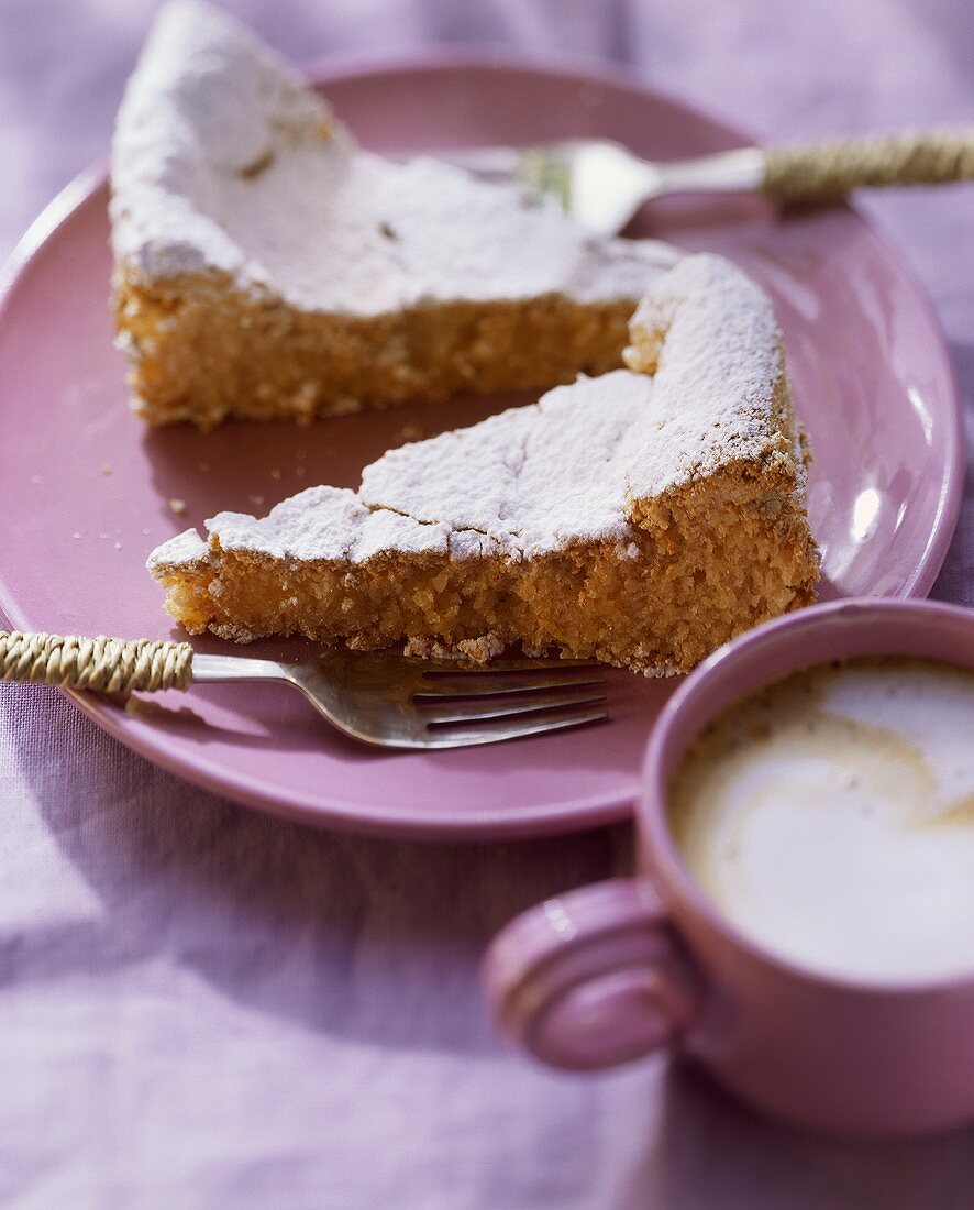 Almond cake with icing sugar on plate; coffee