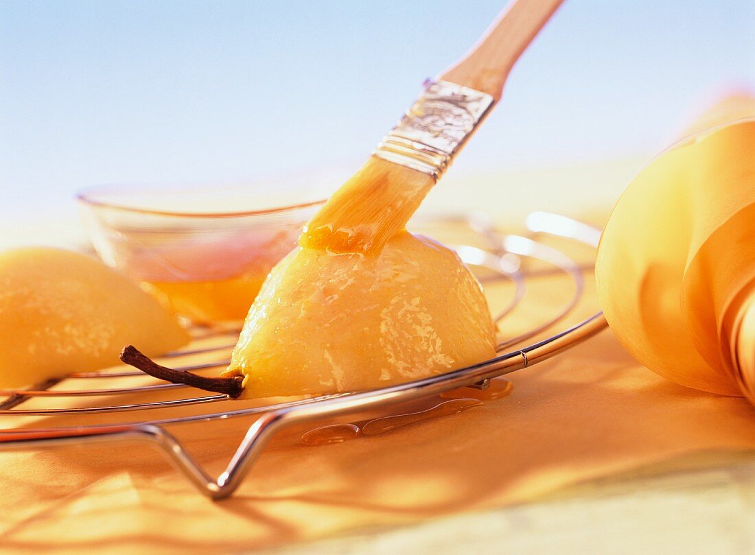 Spreading apricot jam on poached pear