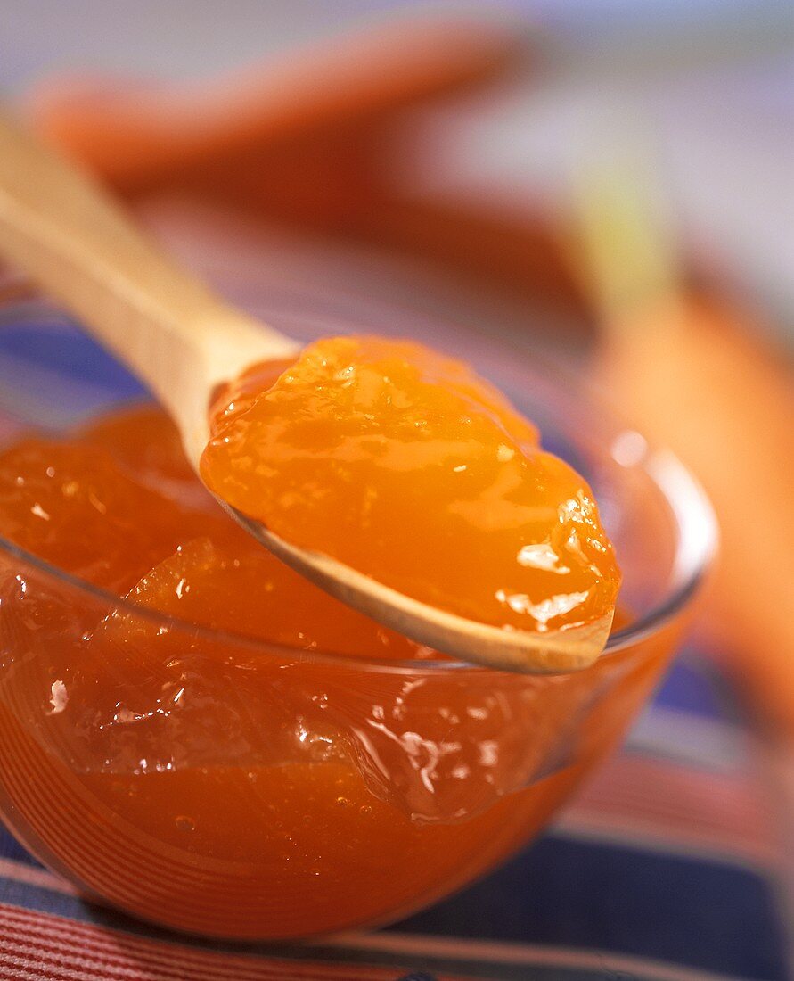 Carrot jelly in bowl and on wooden spoon