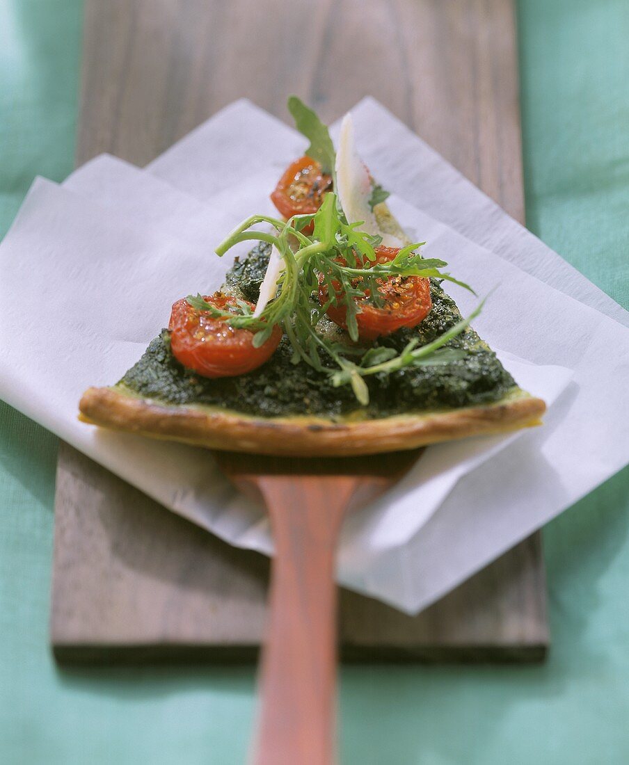 Piece of pizza with rocket, cherry tomatoes and parmesan