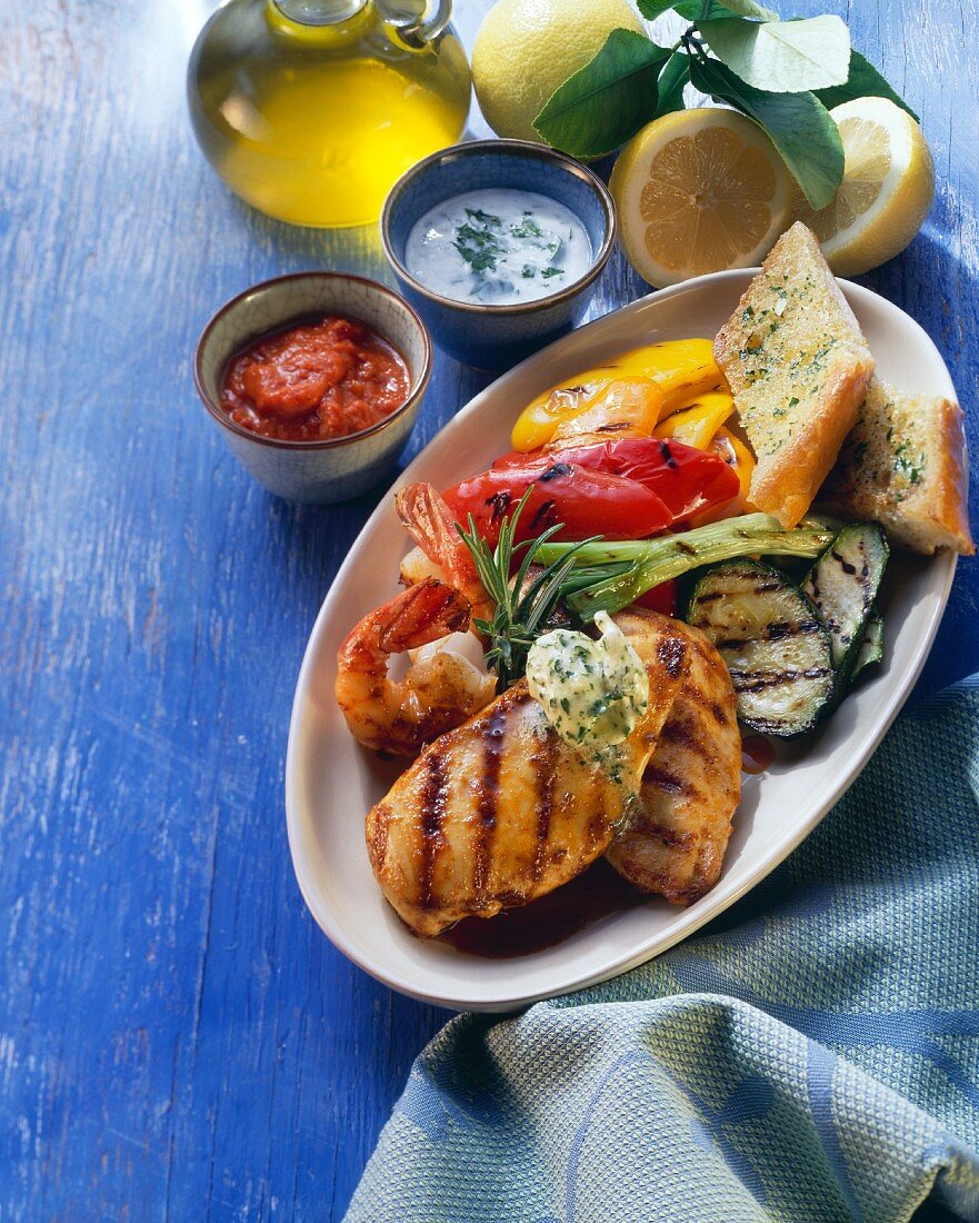 Grillteller mit Hähnchen, Garnelen, Gemüse, Brot, Dips