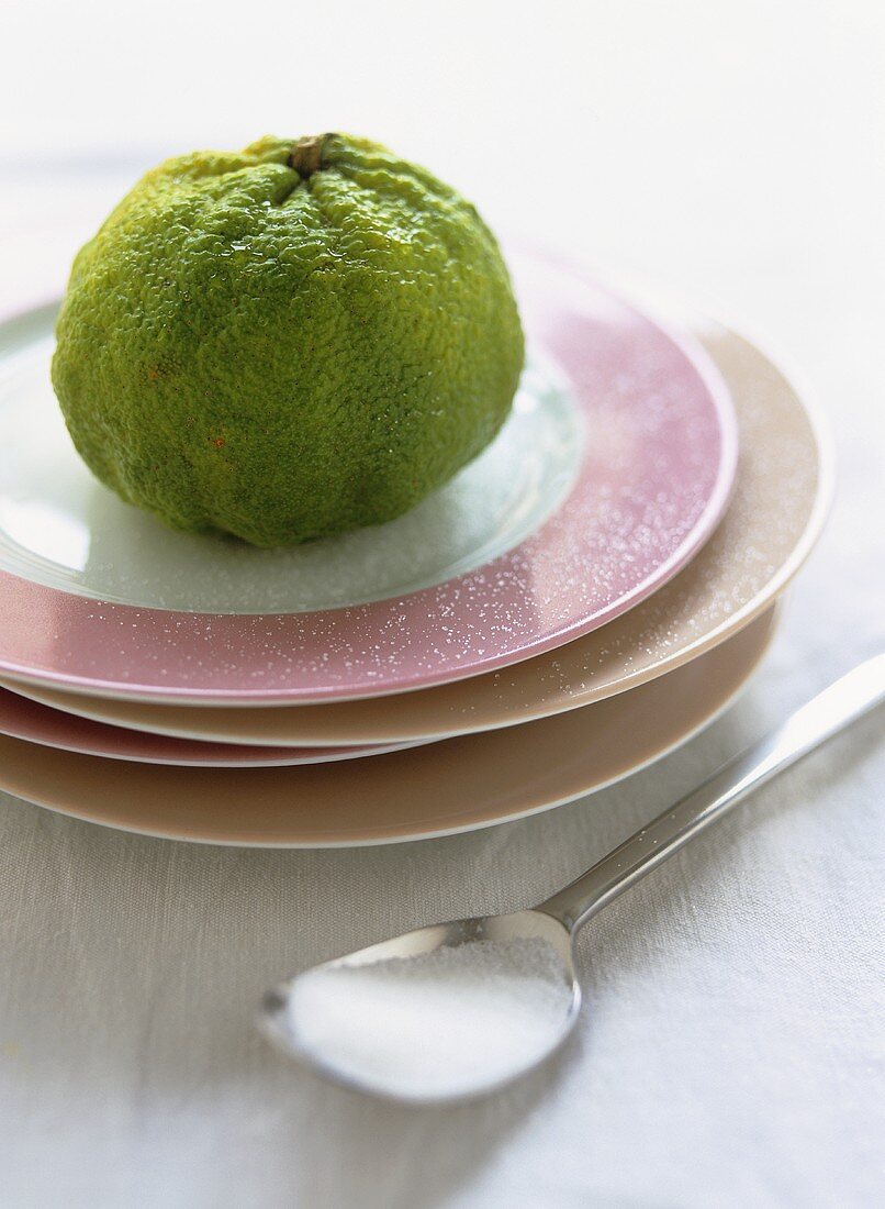Kafir lime on pile of plates; spoon with sugar