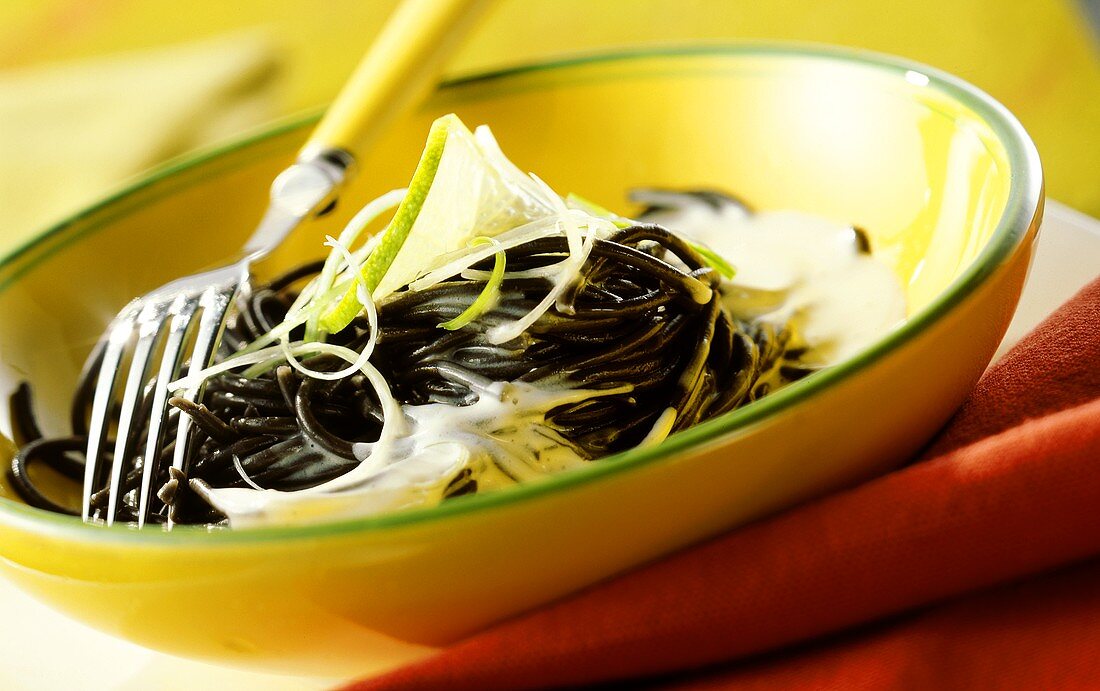 Black spaghetti with goat's cheese sauce and limes