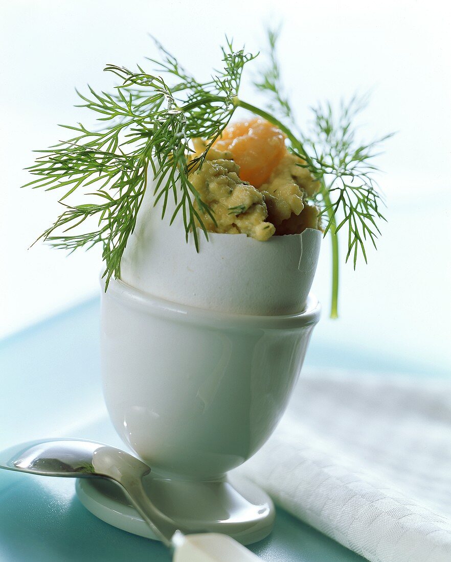 Scrambled egg with shrimps and dill in egg shell in eggcup