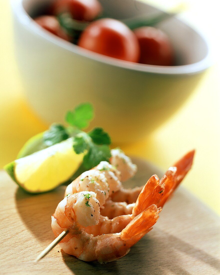 Cooked shrimps on cocktail sticks; lemon; tomatoes