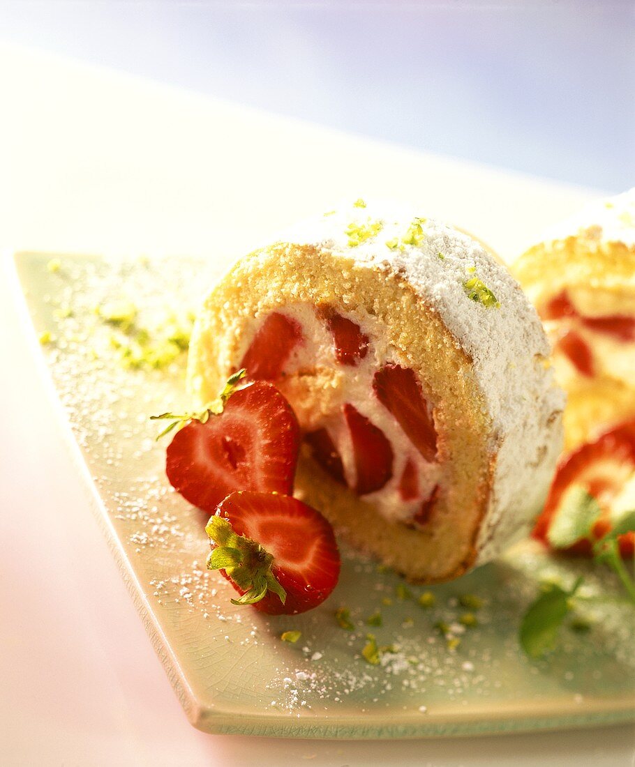 Strawberry roulade with icing sugar and chopped pistachios